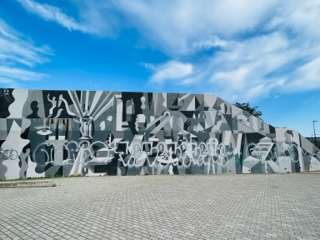 Large grey, black and white design on a wall that shows two sidess of the block wall street art